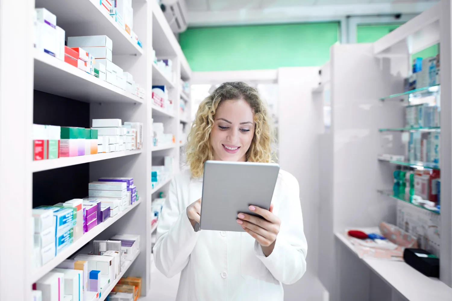Farmacista con tablet tra gli scaffali di medicinali